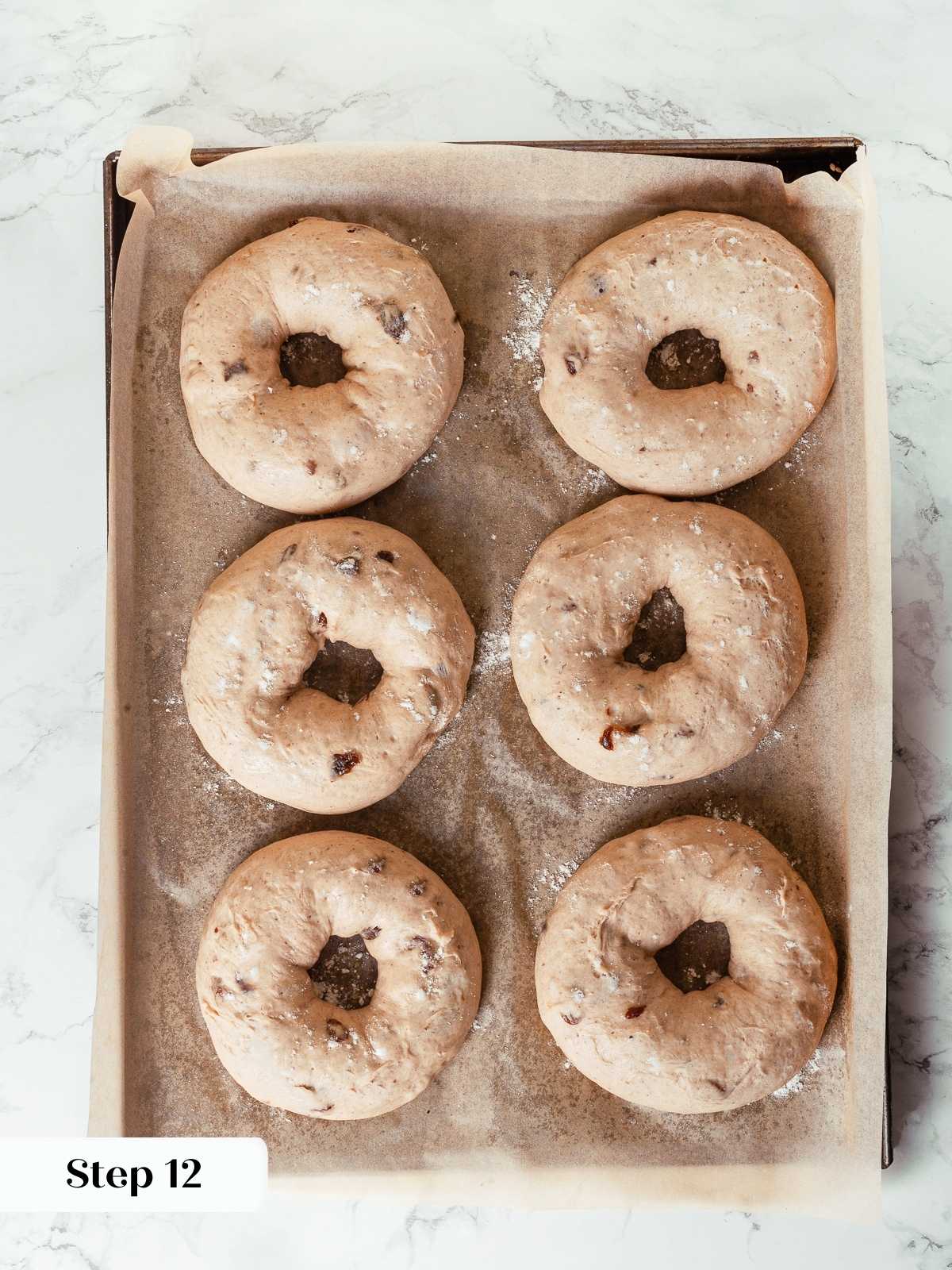 Bagels proofed and puffed on baking sheet, ready for boiling step.