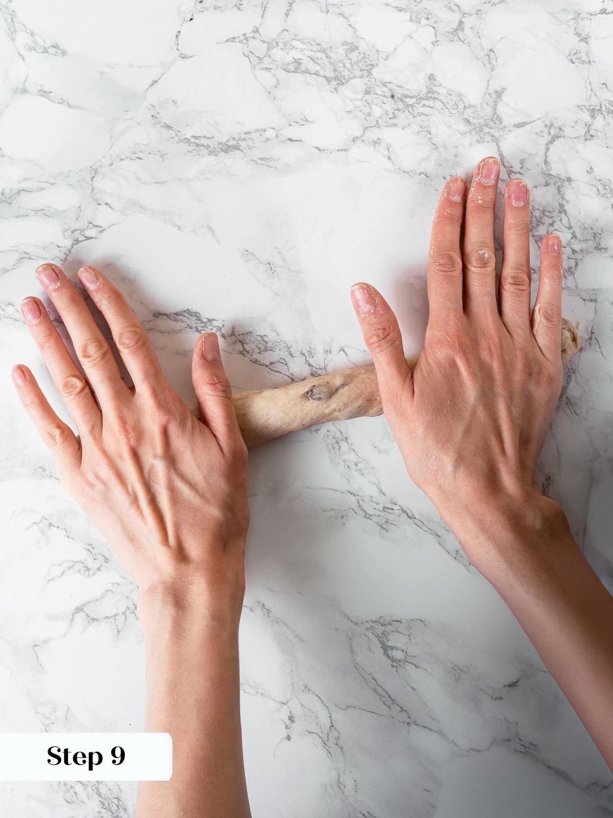 Dough strand being rolled into a rope shape for bagel forming.