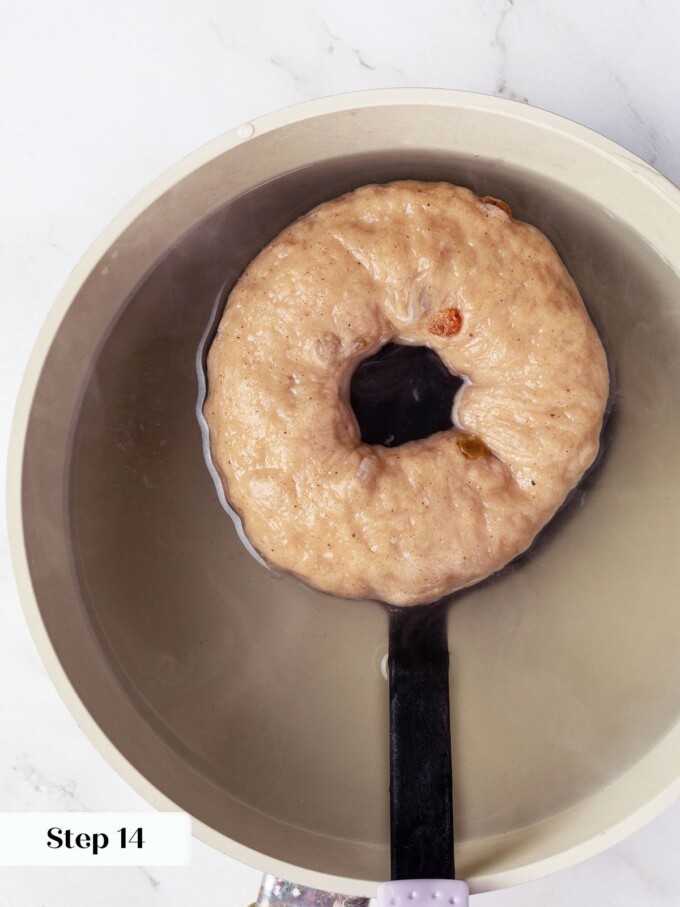 Bagel simmering in water with bubbling edges just before transferring to baking sheet.
