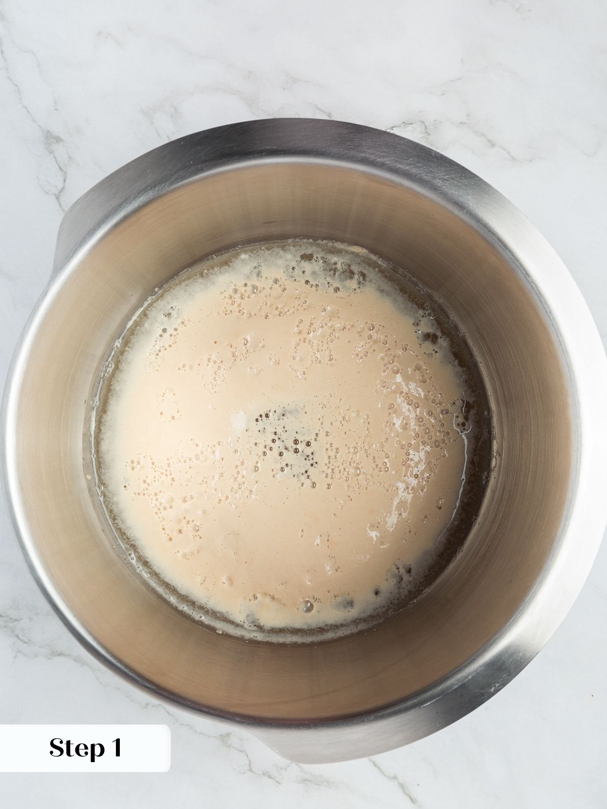 Yeast and water mixture foaming in a bowl before flour is added for dough.