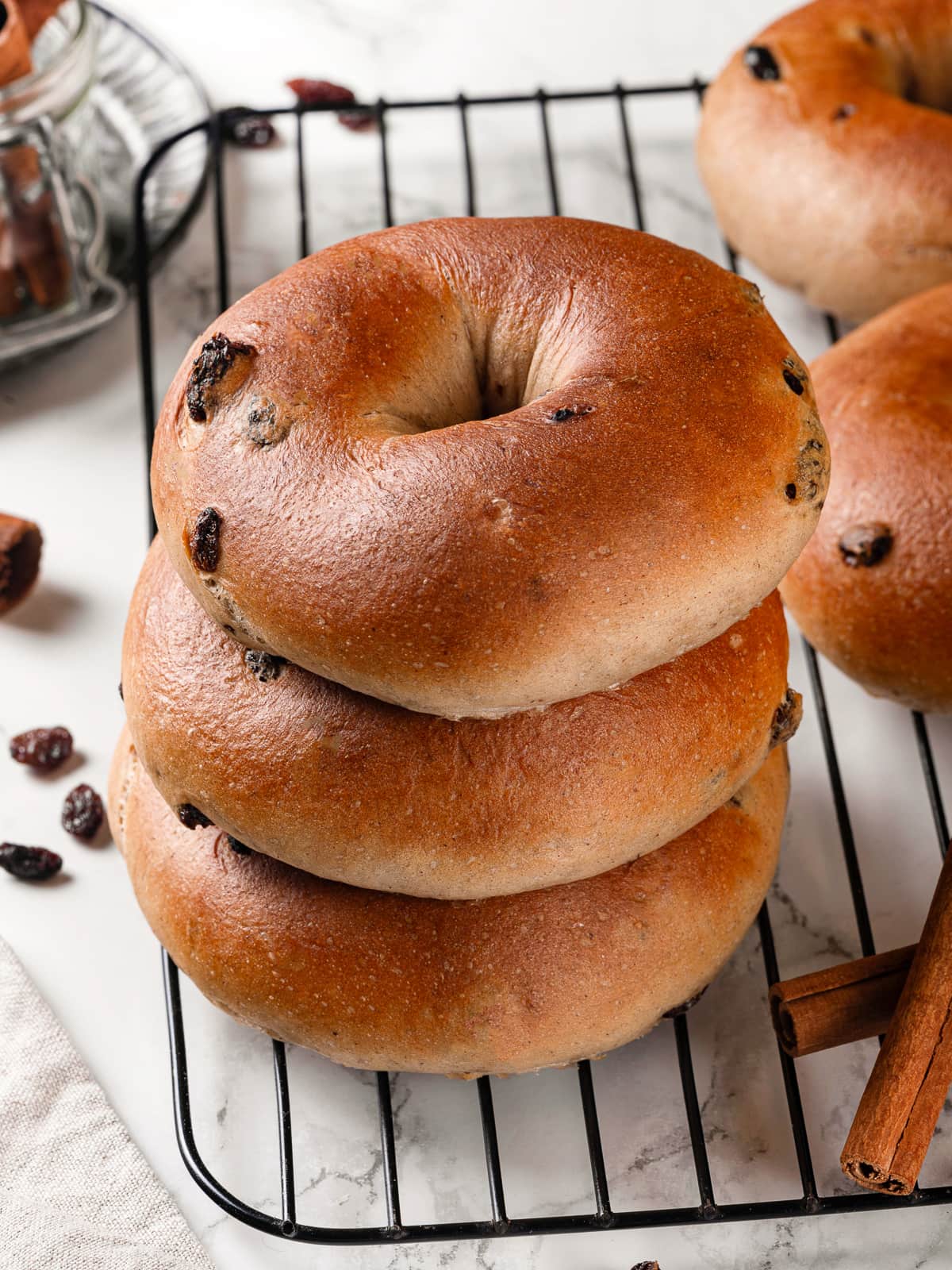 Three stacked bagels with shiny crust and cinnamon flecks.