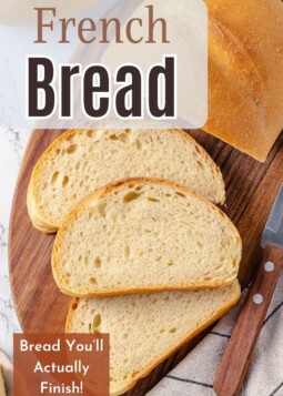 One loaf of French bread sliced to reveal light interior and thin, browned crust.