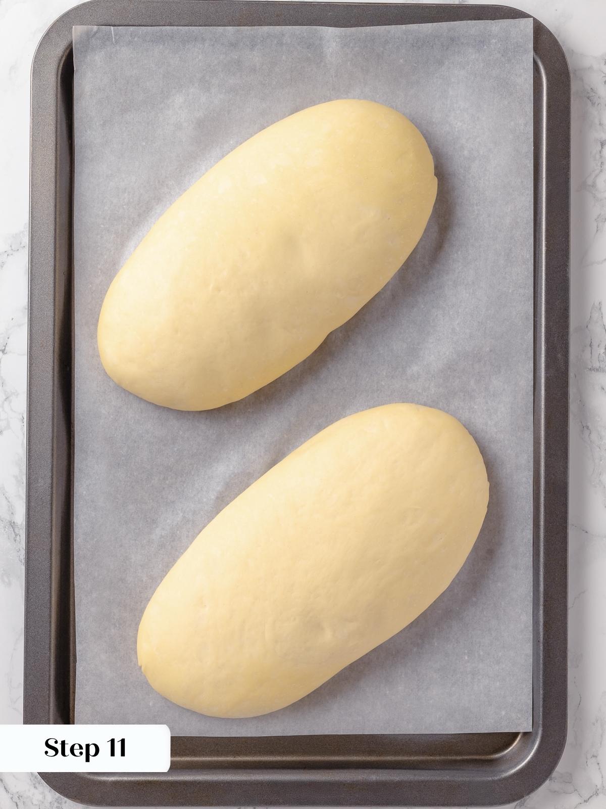 Two loaves of French bread dough after the final rise, puffy and ready for scoring.