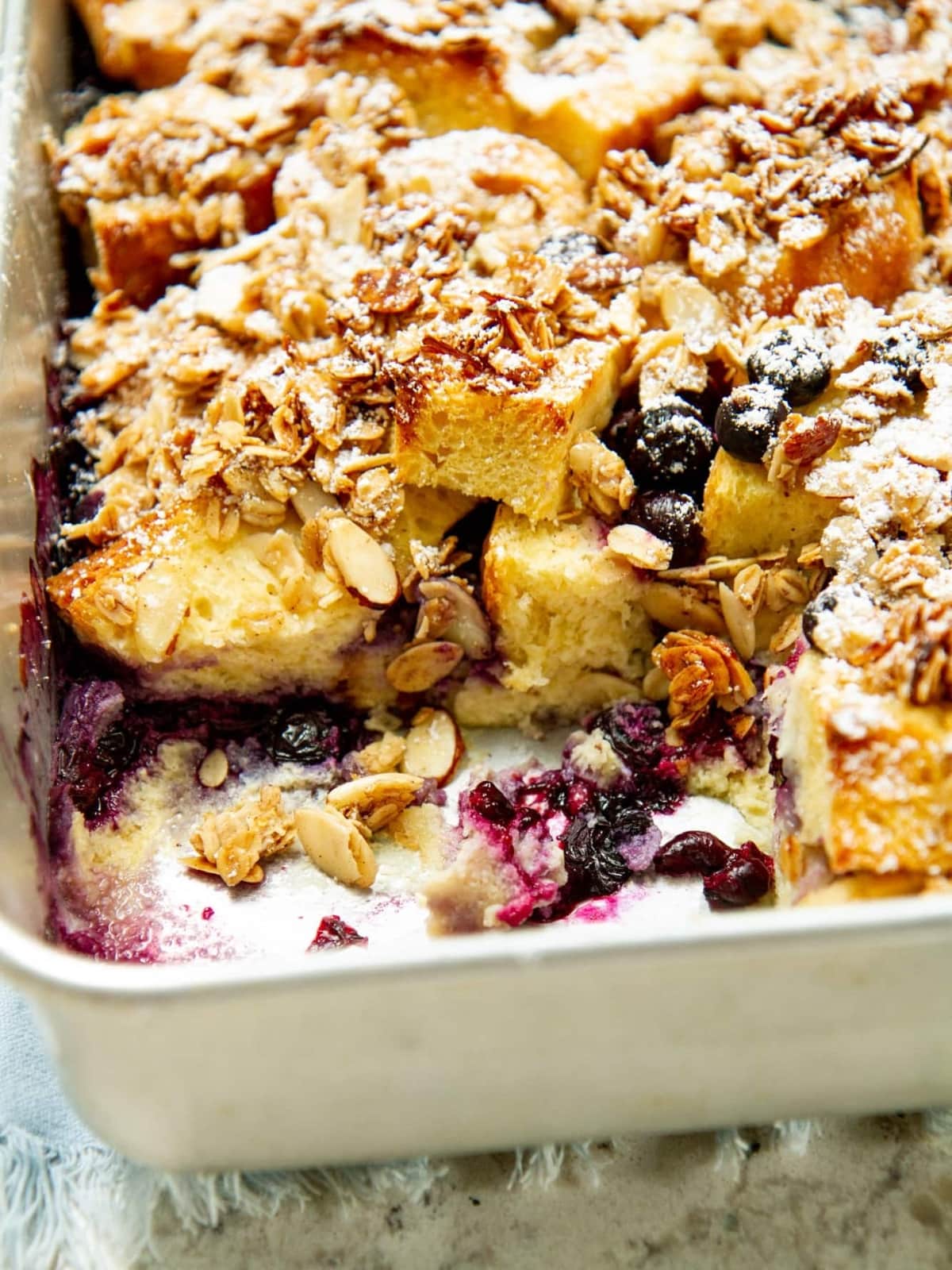 Baking pan with missing piece showing custardy center and streusel topping after slicing.