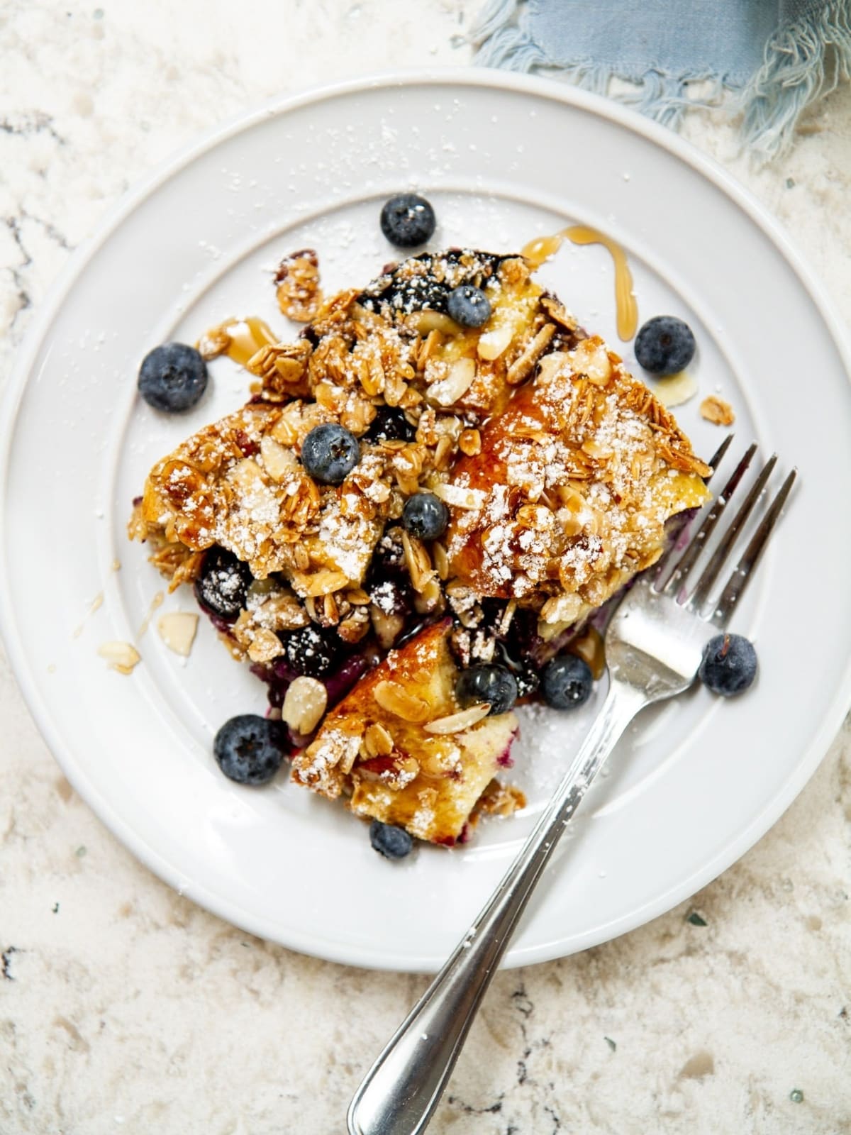 Single slice of French toast casserole served on a white plate with scattered blueberries.