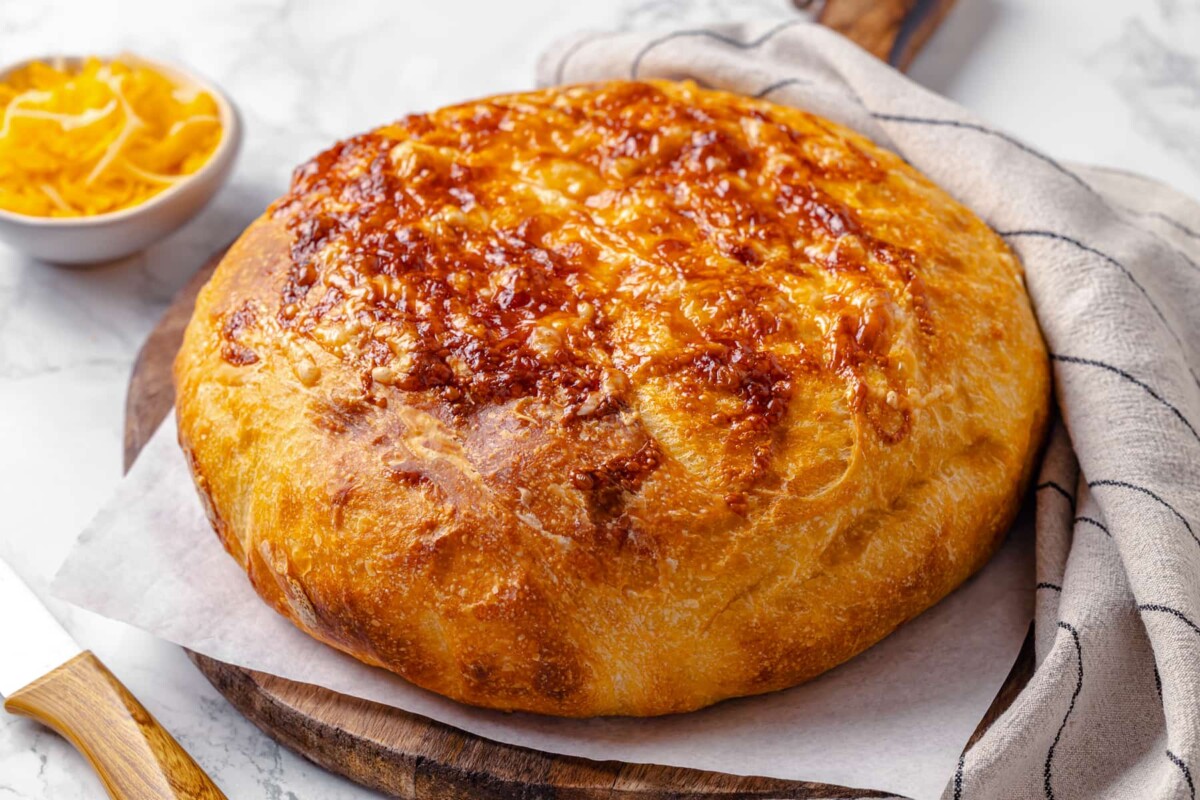 cheese bread on a cutting board beside a serrated bread knife.