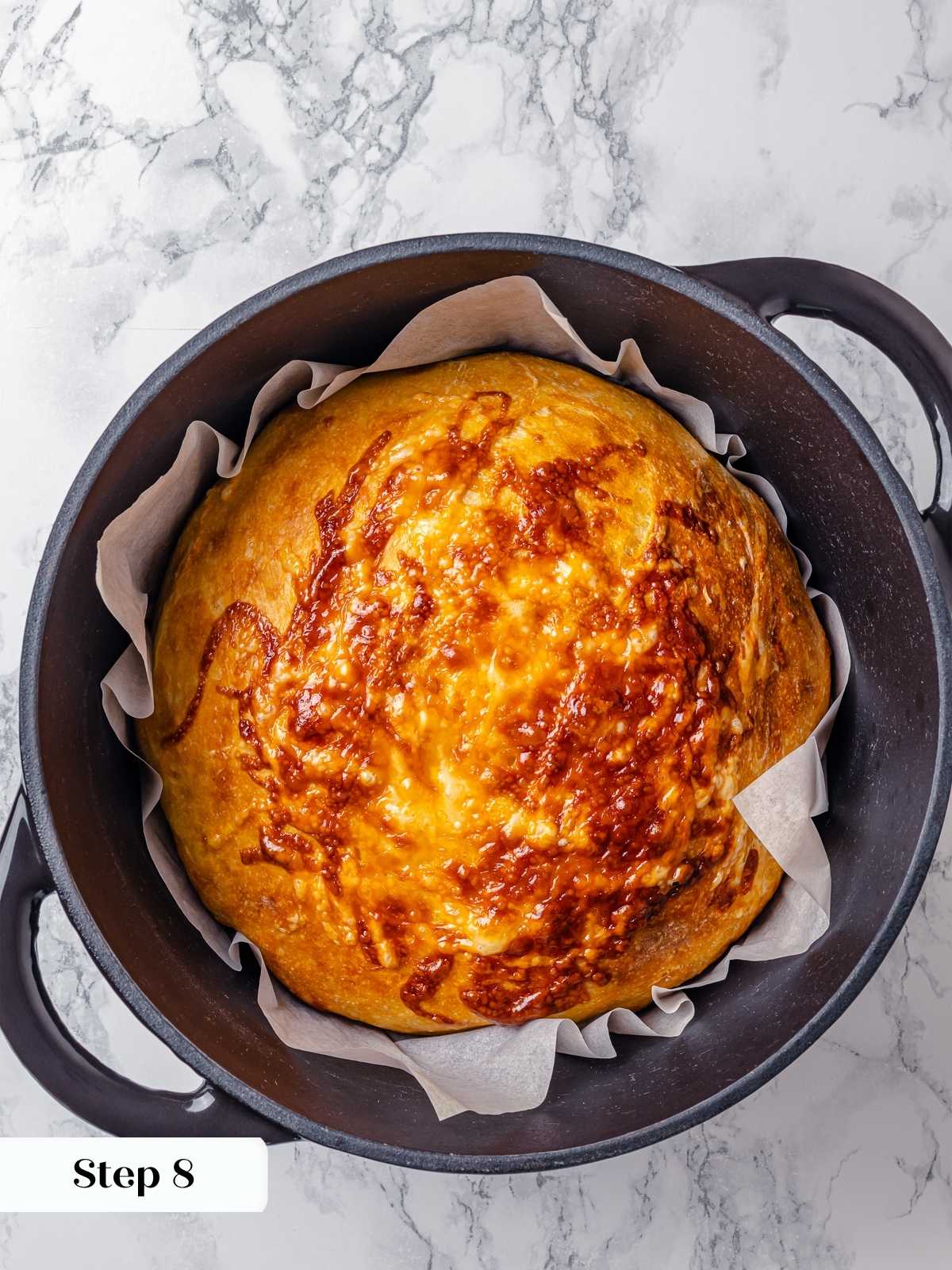 Freshly baked cheese bread in a Dutch oven with crispy crust and melted cheese top.