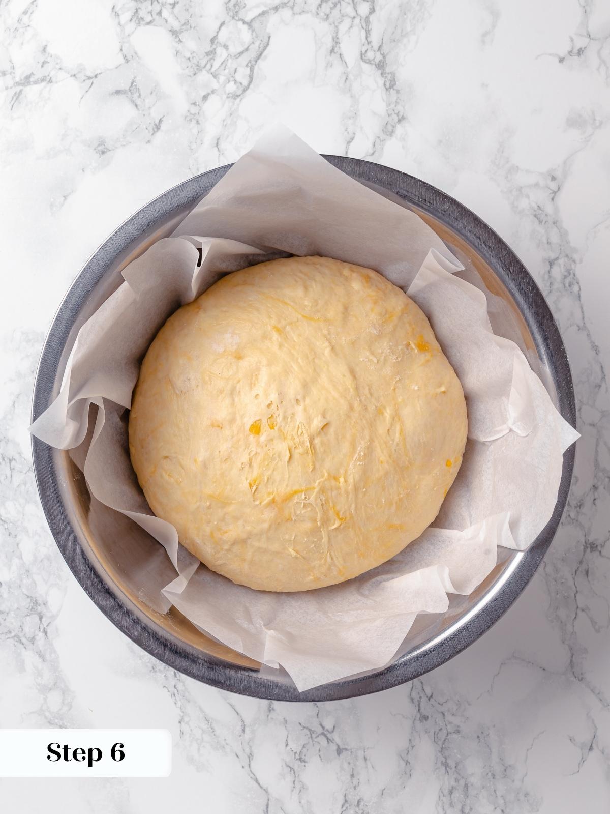 Cheese bread dough in proofing stage, set in parchment-lined bowl for second fermentation.