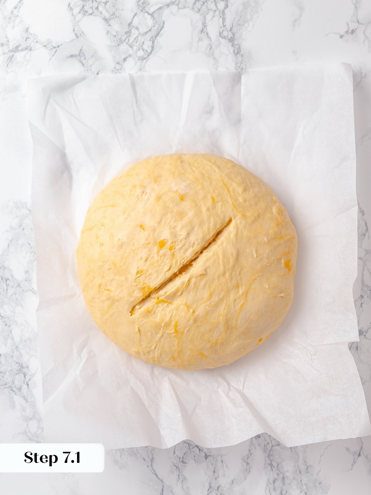 Round dough scored deeply before baking to help shape rise and hold cheese topping.