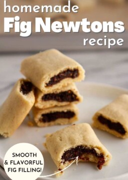 Stack of fig newton cookies on a plate with one cookie showing a bite taken out to show the fig filling.