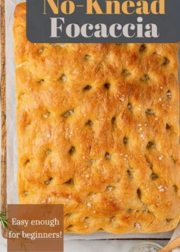 Freshly baked focaccia with golden edges on a wooden board.