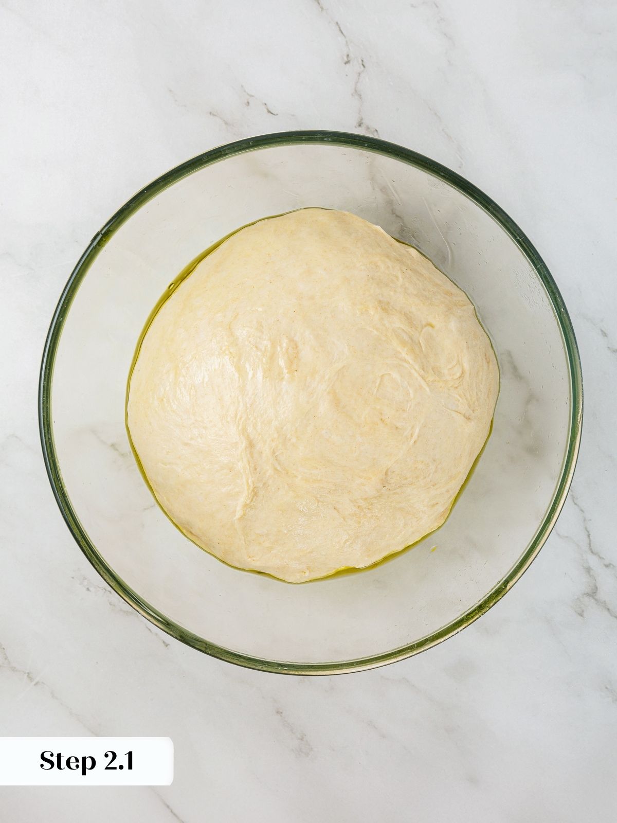 Just-mixed dough sitting in a bowl before bulk rise with olive oil sheen.