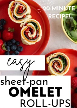 Three sheet-pan omelet roll-ups filled with spinach, red pepper, and ham on a red plate, served with fresh blueberries and strawberries.