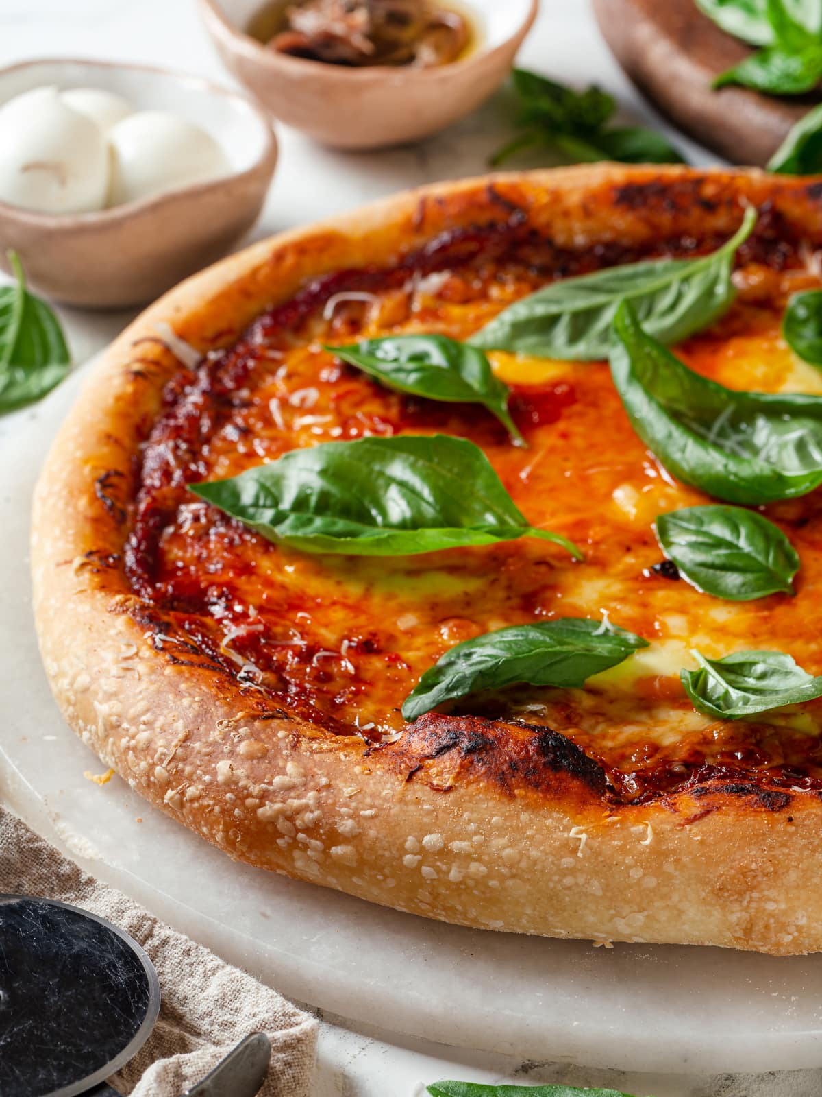 Fresh basil leaves on top of sourdough discard pizza crust with melted cheese.