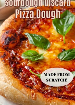 Homemade sourdough discard pizza dough stretched into a round crust topped with melted cheese and sauce.