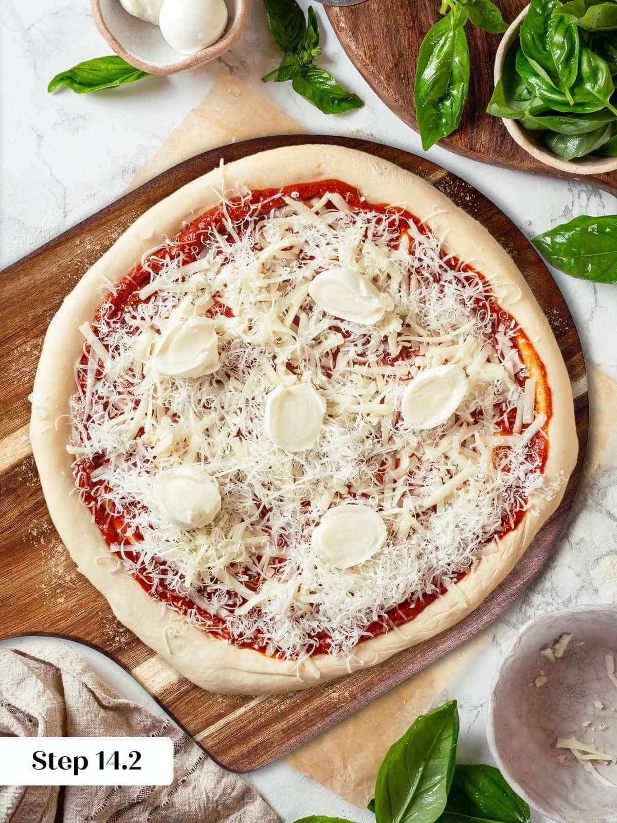 Pizza dough topped with shredded cheese before baking in oven.