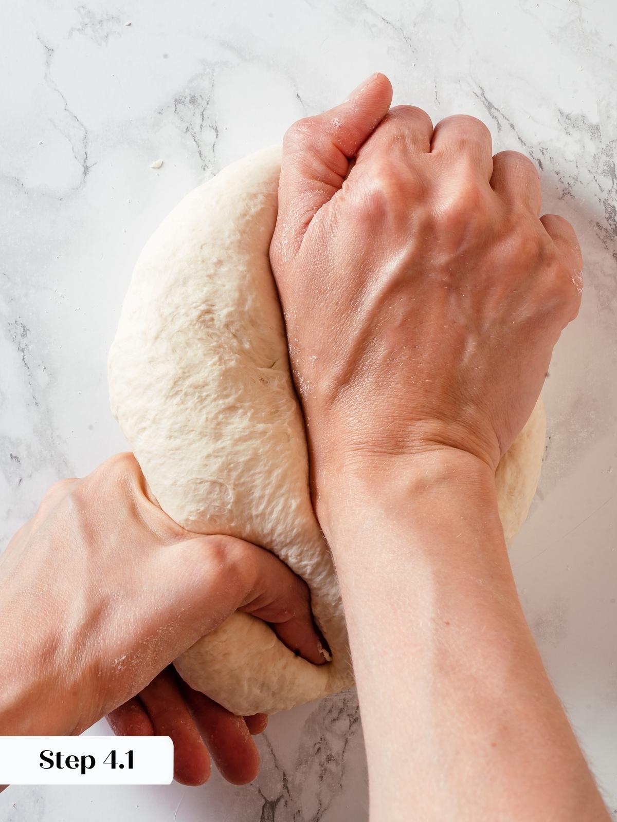 Hands kneading sourdough discard dough on countertop to develop texture and structure.