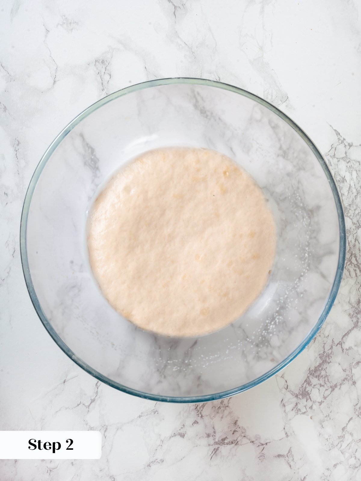 Bowl with yeast and warm water combining as first step in sourdough discard pizza dough.
