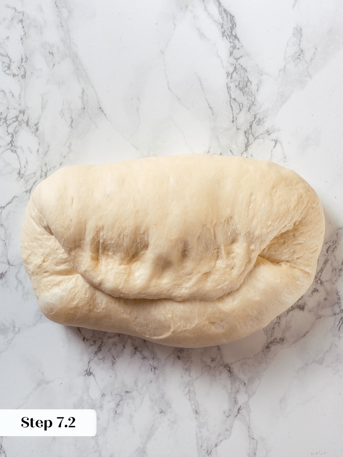 Dough folded a second time into thirds during shaping of sourdough sandwich loaf.