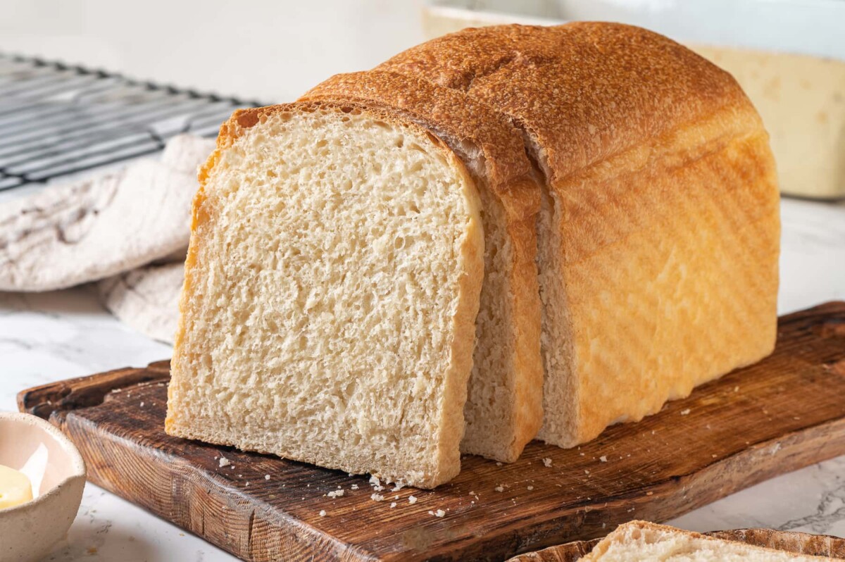 Sliced sourdough sandwich bread revealing a soft inside with golden crust and airy crumb.
