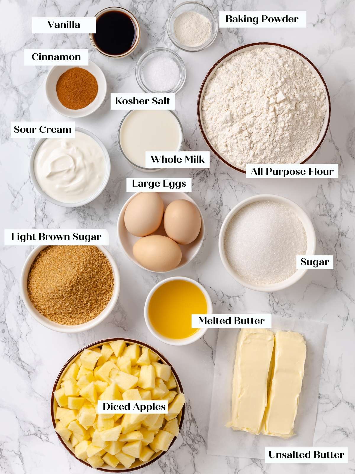 Baking ingredients like apples, sugar, and flour arranged on countertop before preparing cake.