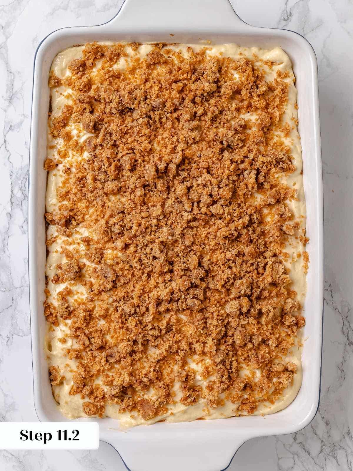 Unbaked crumb topping sprinkled over batter in pan before baking apple coffee cake.