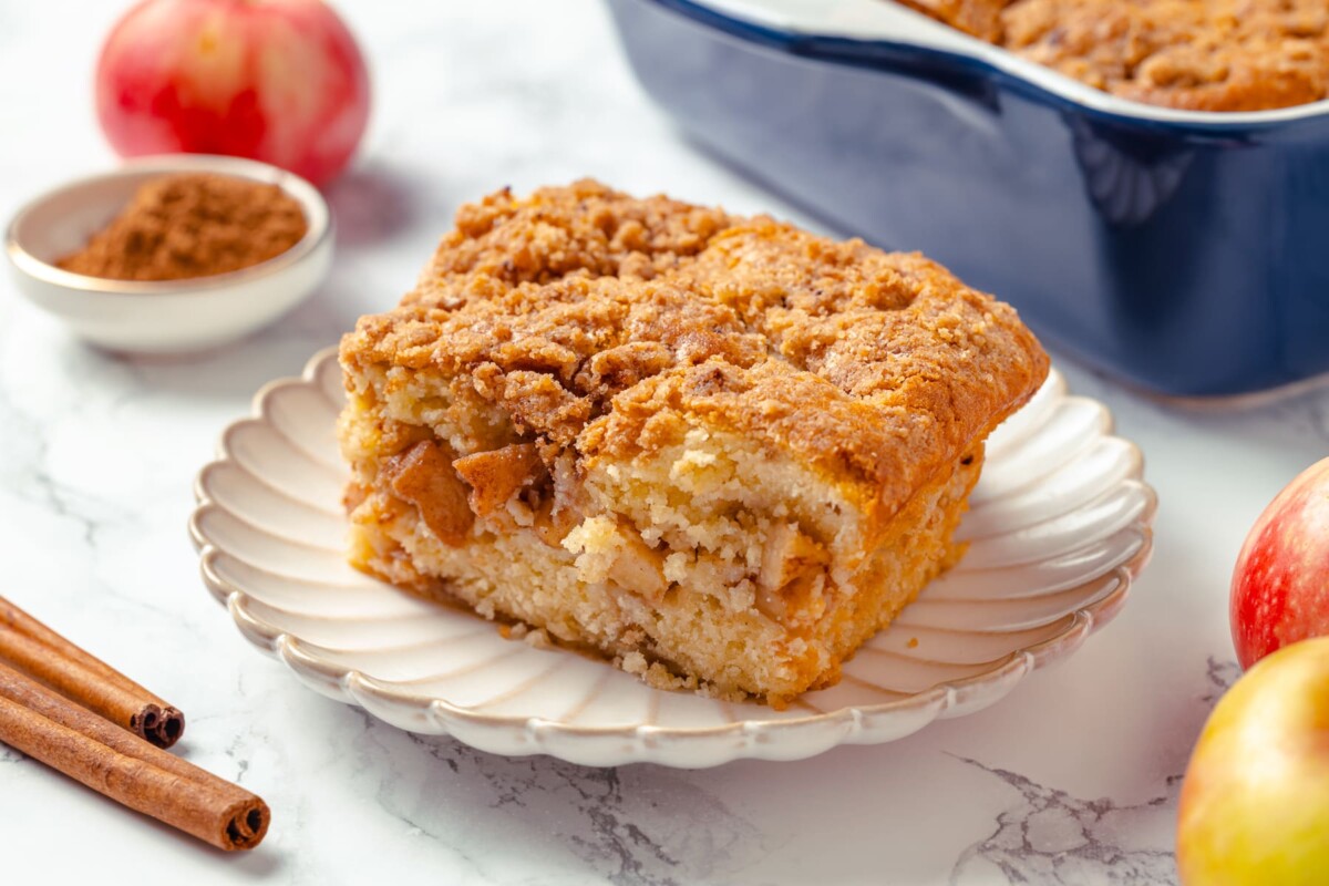 Square piece of apple coffee cake with cinnamon crumb topping and tender apple-filled layers inside.