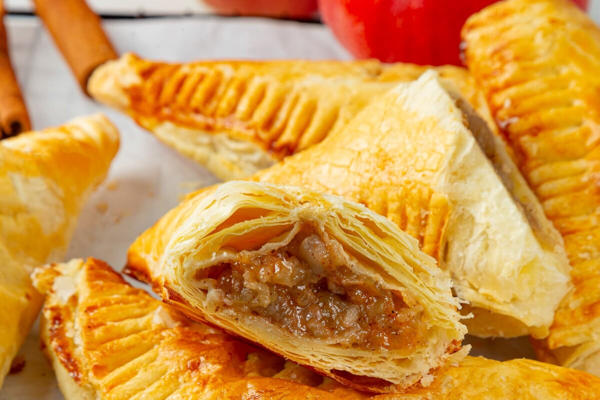 Close look at apple turnovers showing distinct flaky puff pastry layers with baked golden finish.