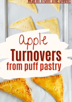Flaky apple turnovers arranged on a baking tray, with steam rising and layers visibly puffed.