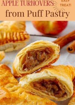 Freshly baked apple turnovers with puff pastry on parchment paper, showing flaky layers and golden crust.