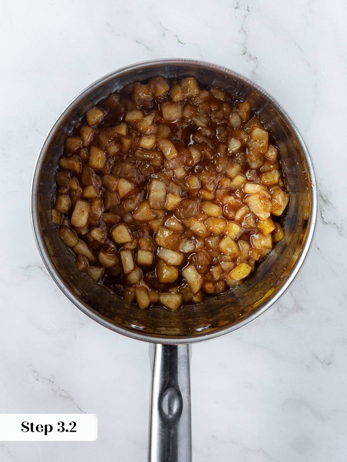 Apple filling in saucepan after thickening with cornstarch, showing tender apple chunks coated in sauce.