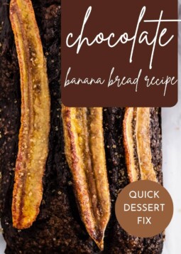 Chocolate banana bread loaf topped with a sliced banana and sugar crystals, resting on parchment paper.