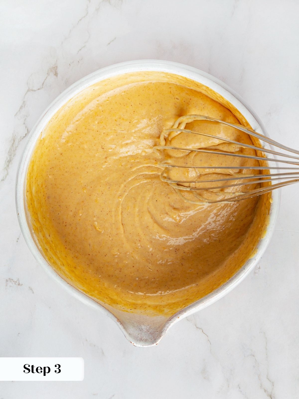 Smooth pumpkin pancake batter whisked in a mixing bowl, thick and ready for cooking pancakes.
