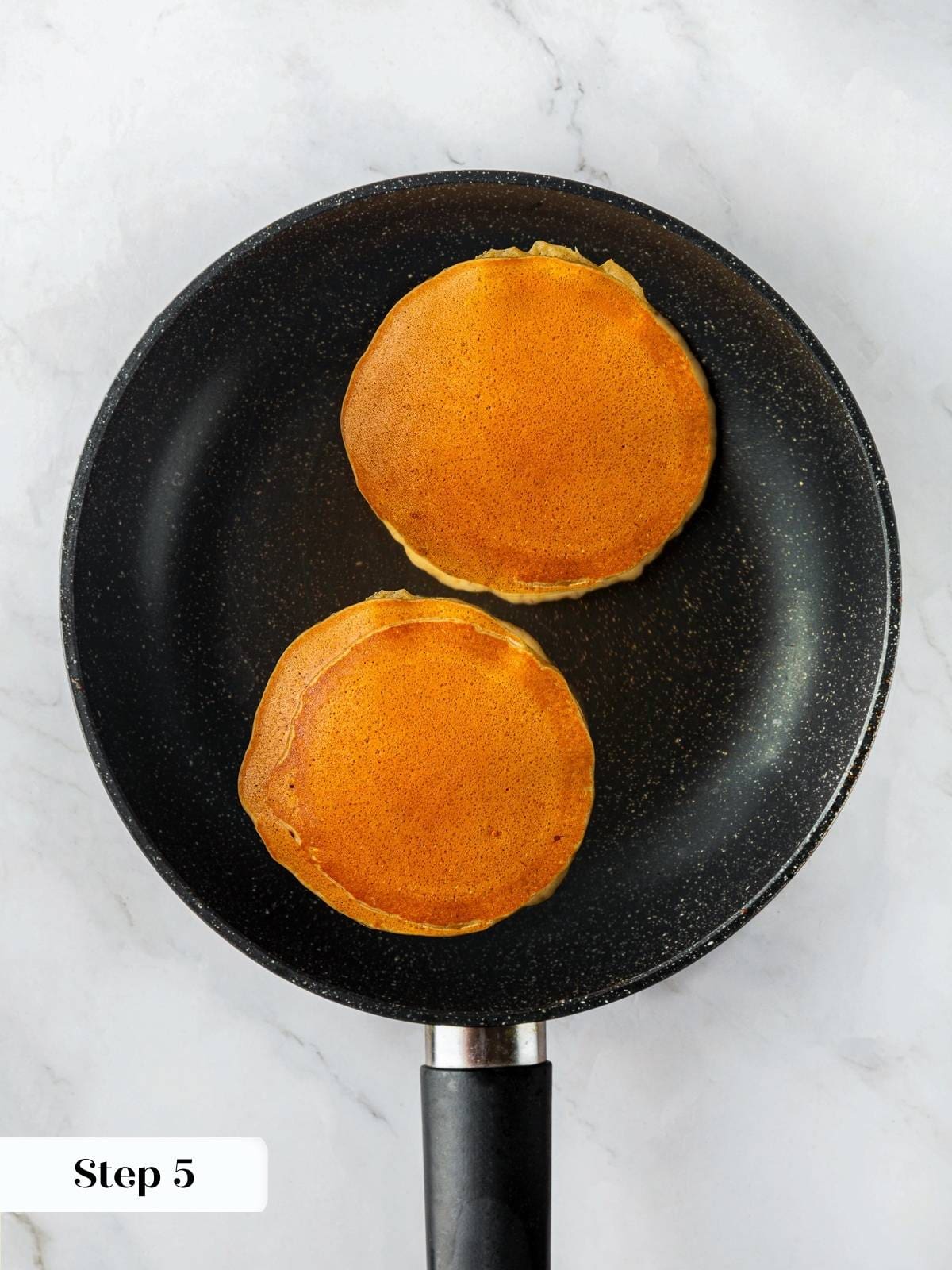cooked tester pancakes rests in the skillet, testing heat before making more.