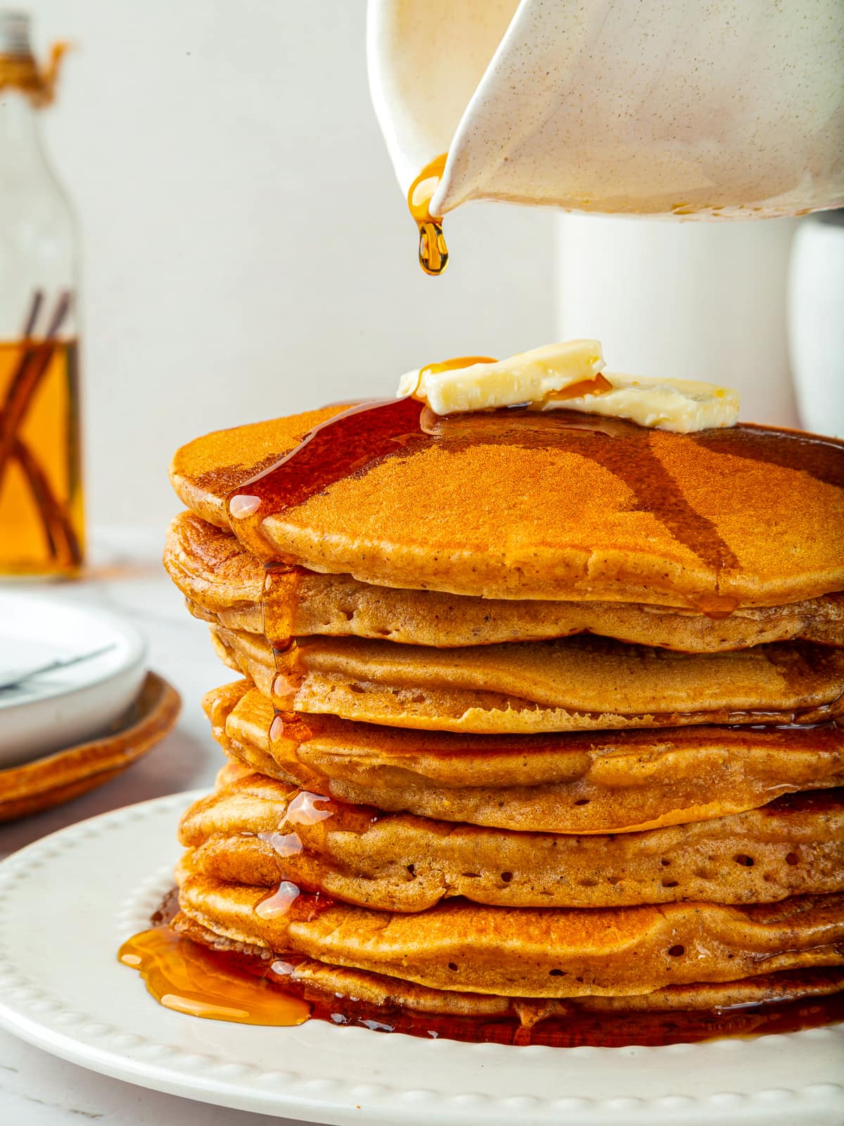 Sweet maple syrup dripping slowly from stacked pumpkin pancakes, glistening on the golden edges.