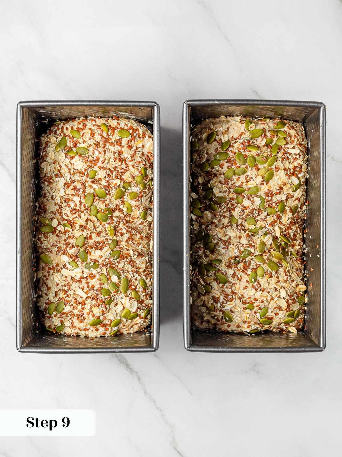 Seeded dough rising in loaf pans before baking.