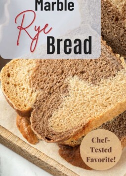 Slices of marble rye bread stacked on a wooden board.
