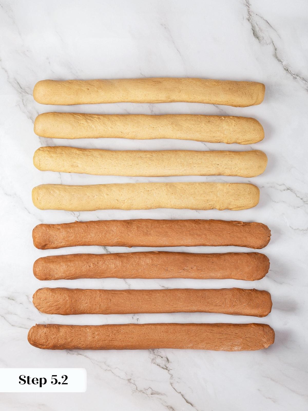 Rolled strands of light and dark rye dough laid out for braiding the loaf.