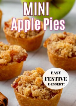 Mini apple pies with cinnamon apple filling, cooling on parchment paper with crumbs scattered around.