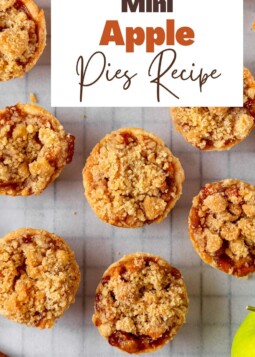 Golden mini apple pies arranged on a tray with flaky crusts and sweet cinnamon apple filling.
