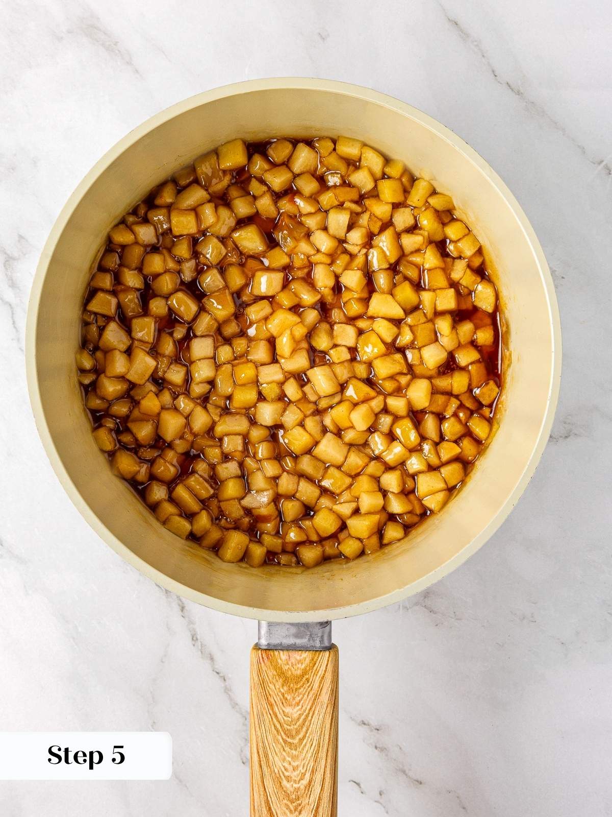 Apples cooking in a saucepan with cinnamon, sugar, and lemon juice for pie filling.