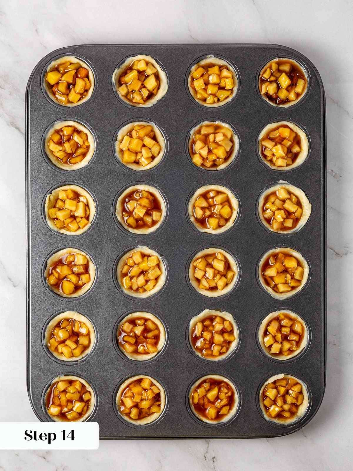 Tart apple filling portioned into pressed cream cheese crusts before baking.