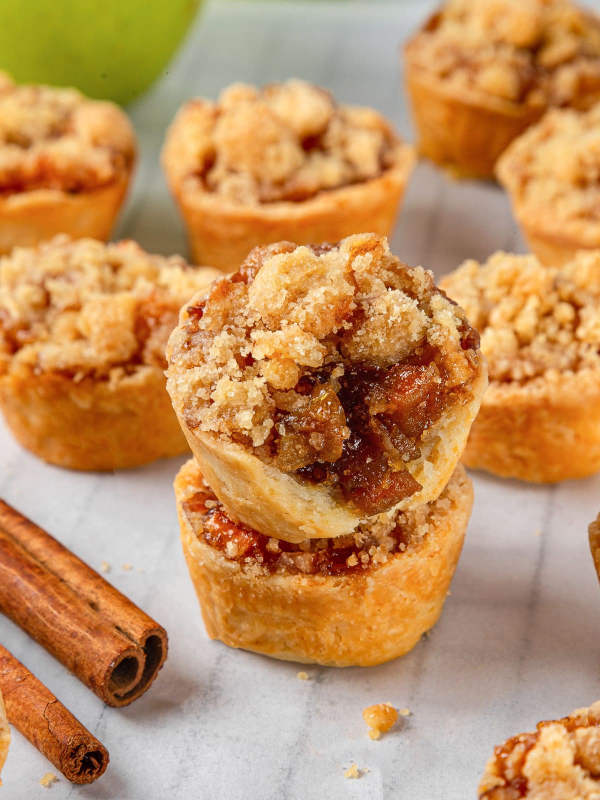 Two golden brown mini apple pies stacked on top of each other with crumble topping.
