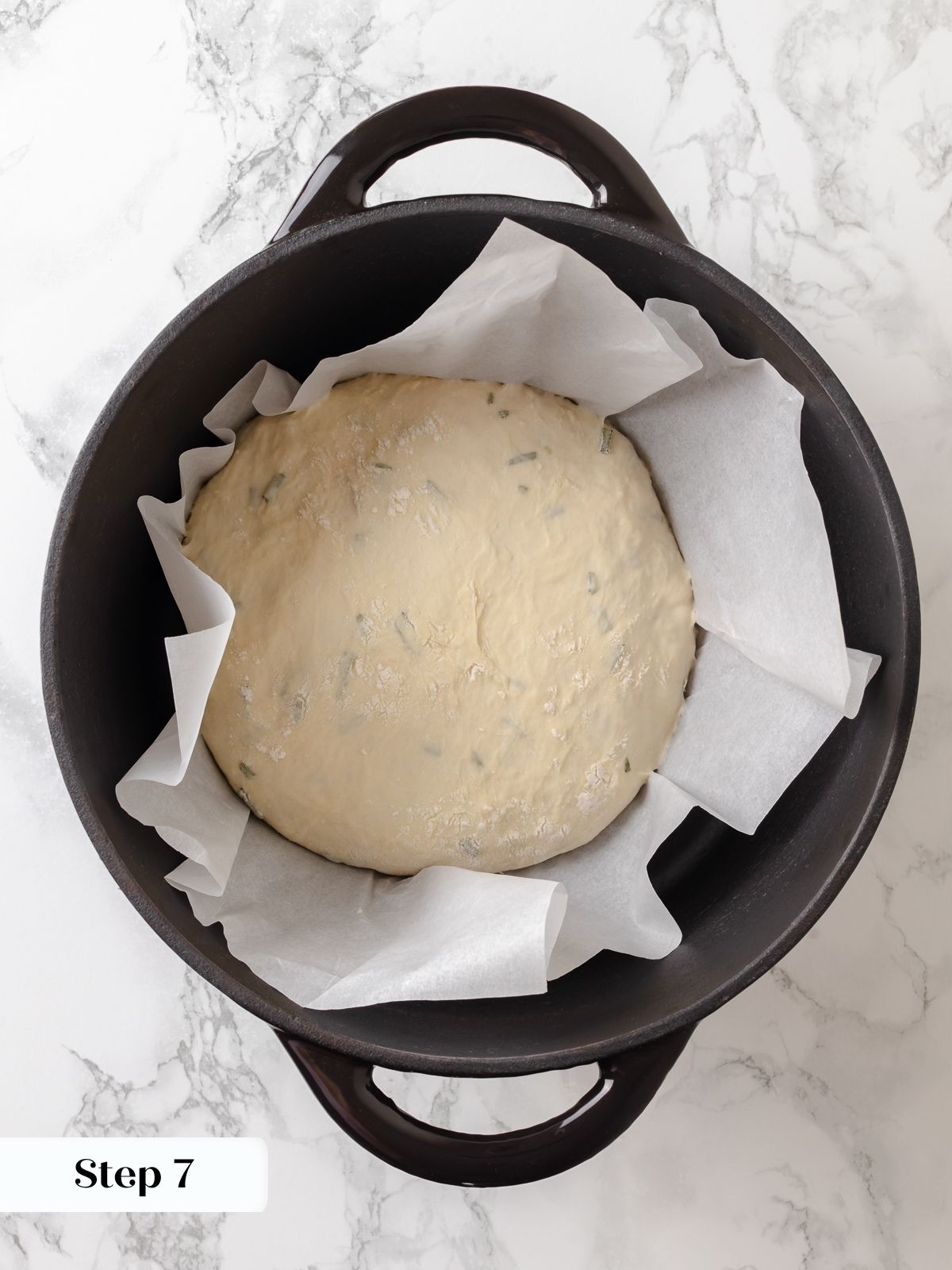 Dough for rosemary bread placed in a Dutch oven lined with parchment paper before baking.