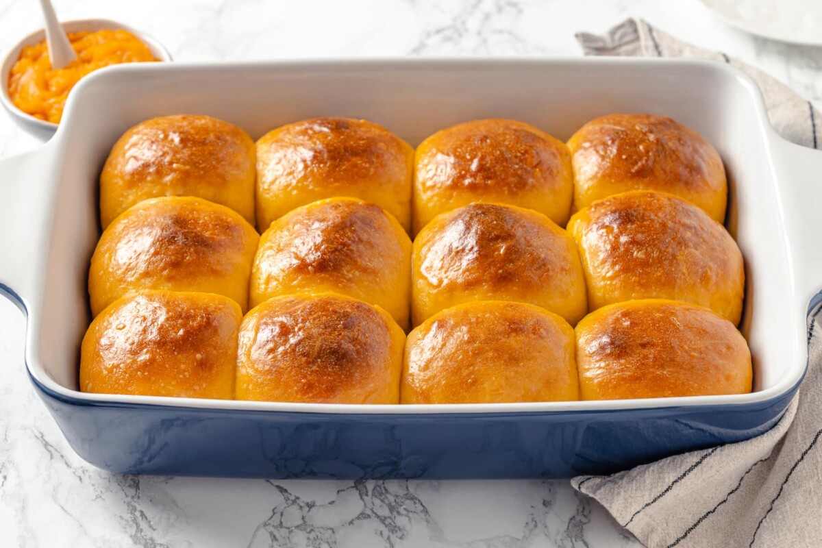 Blue baking dish filled with warm, golden sweet potato rolls fresh from the oven.