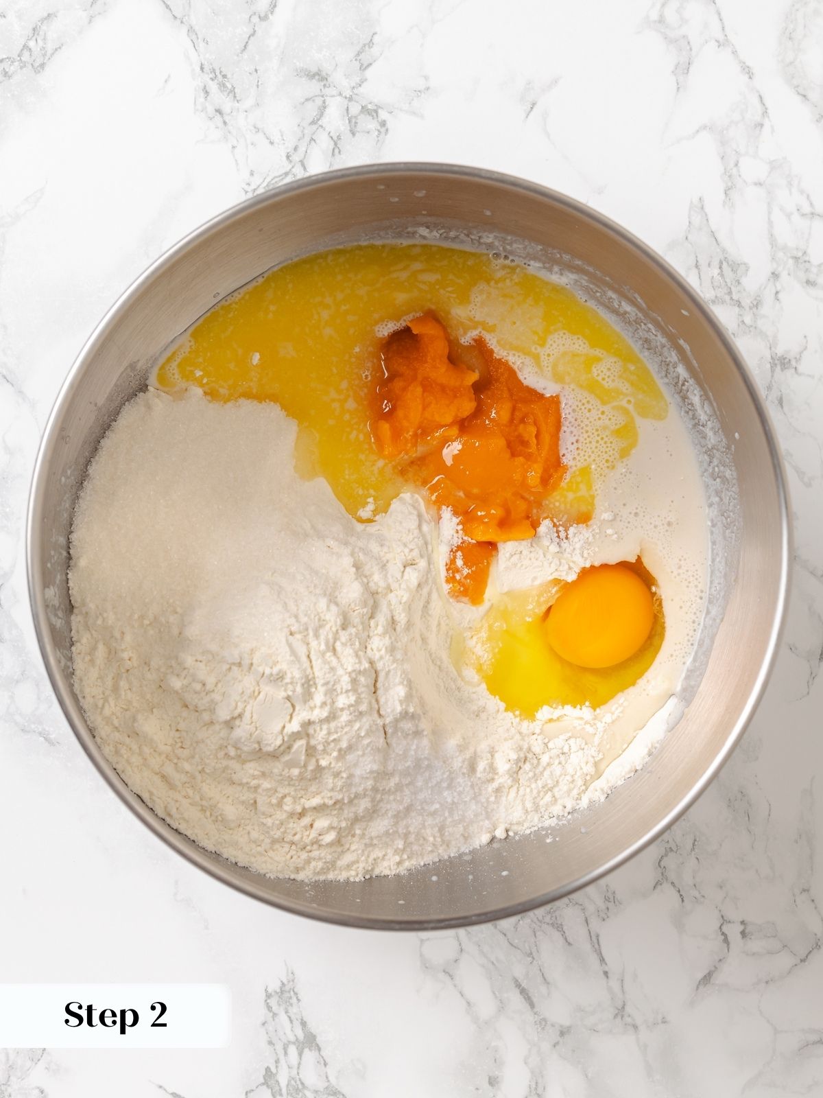 Ingredients for sweet potato dough in a mixing bowl before combining into a smooth mixture.