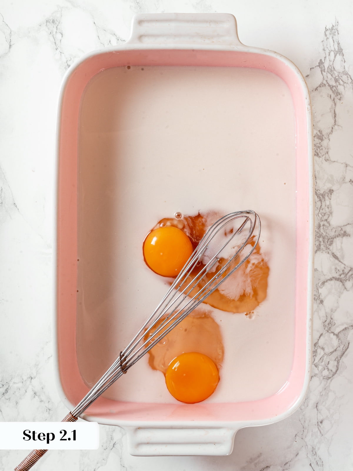 Mixing custard ingredients together in a dish to prepare the batter for brioche French toast.