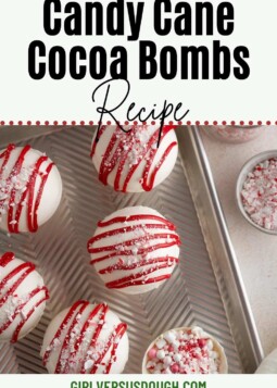 White candy cane cocoa bombs drizzled with red white chocolate and crushed candy canes.