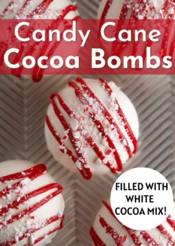 White candy cane cocoa bombs drizzled with red white chocolate and crushed candy canes.