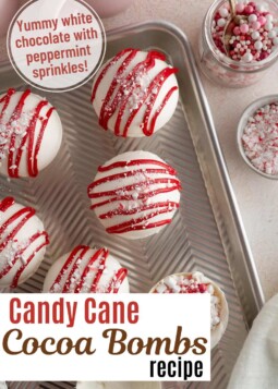 White candy cane cocoa bombs drizzled with red white chocolate and crushed candy canes.